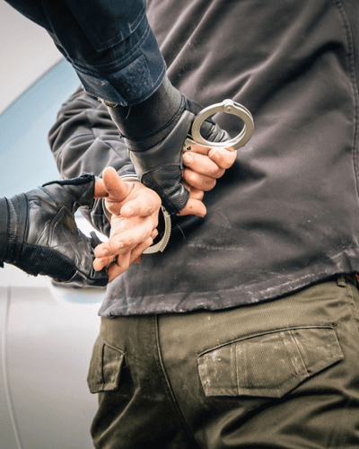 a man being arrested for homicide with his hands in handcuffs