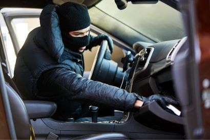 a man in a black ski mask stealing things inside a car